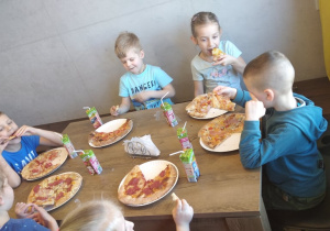 Sześcioro dzieci je przygotowane przez siebie pizze