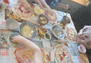 Dzieci z grupy czwartej wykładają ulubione składniki na swoje pizze