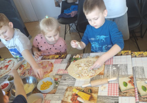 Troje dzieci wykłada składniki na pizze