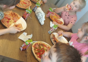 Sześioro dzieci je przygotowane przez siebie pizze