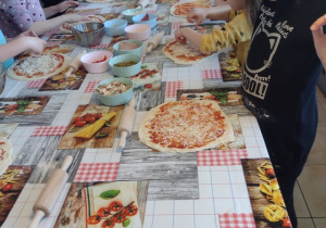 Dzieci nakładają ser żółty na swoje pizze