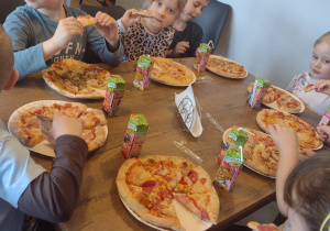 Sześcioro dzieci je swoje wykonane pizze