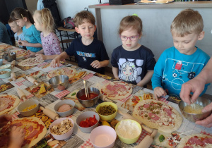 Sześcioro dzieci nakłada swoje ulubione składniki na pizze