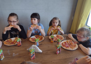 Cztery dziewczynki jedzą swoją pizzę