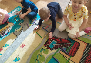 Troje dzieci układa obrazki z kolorowych patyczków