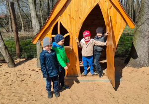 Czworo dzieci z grupy II bawią się w drewnianym domku