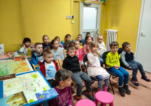 Dzieci z grupy V słuchają bajki czytanej przez panią bibliotekarkę
