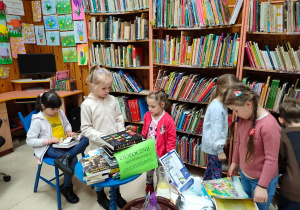 Dzieci z grupy V oglądaja książki biblioteczne