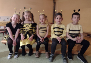 Pięcioro dzieci w przebraniach pszczółek siedzi na ławce