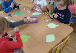 Przedszkolaki robią małe kółka z kolorowych pasków papieru