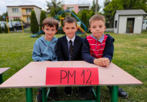 Trzech chłopców siedzi przy stoliku podczas konkursu