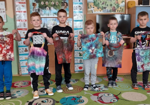 Sześć chłopców pokazuje swoje torby zabarwione farbami do tkanin