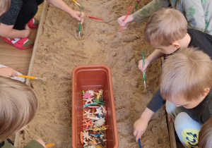 Dzieci z grupy drugiej wykopują przedmioty z piasku