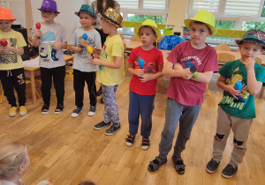 Siedmiu chłopców stoi podczas jednej z piosenek w kolorowych kapeluszach i z grzechotkami