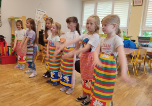 Siedem dziewczynek tańczy w kolorowych fartuszkach