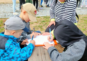 Trzech chłopców podpisuje regulamin Zielonego Przedszkola