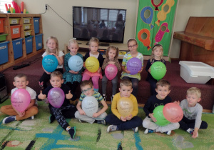 Przedszkolaki z grupy piątej siedzą z balonami otrzymanymi na Dzień Przedszkolaka