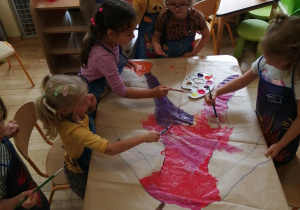 Dziewczynki z grupy trzeciej malują dziewczynkę z przedszkola