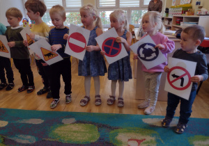 Kilkoro dzieci stoi z namalowanymi znaki drogowymi podczas piosenki
