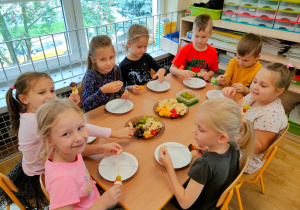Ośmioro dzieci przygotowuje owocowe szaszłyki