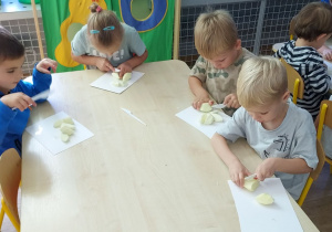 Czworo dzieci kroi owoce na mniejsze kawałki