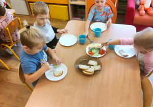 Czworo dzieci z grupy pierwszej przygotowuje sobie kanapki