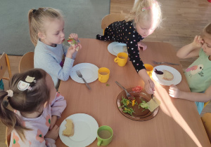 Czworo dzieci z grupy trzeciej je kanapki przygotowane przez siebie