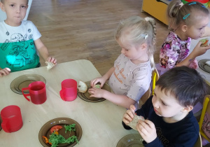 Czworo dzieci z grupy drugiej jedzą kanapki przygotowane przez siebie