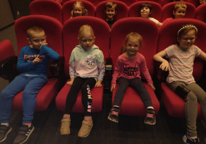 Ośmioro dzieci siedzi w fotelach czekając na przedstawienie