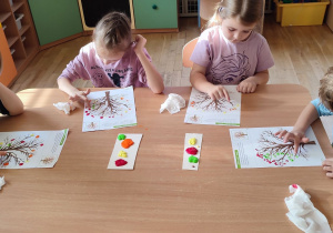 Czworo dzieci maluje placami drzewa jesienne