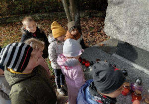 Dzieci z grupy IV stoją przy pomniku żołnierzy