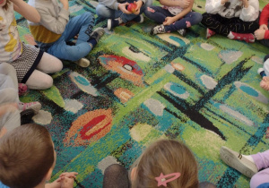Dzieci siedzą w kole i bawią się w "Zatrute jabłko" - przekazują sobie owoc, gdy gra muzyka