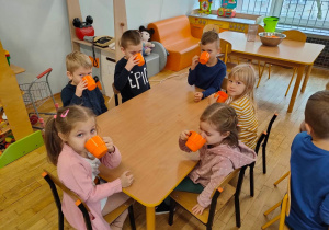Szóstka dzieci pije świeżo wyciskany sok z marchewki i jabłka