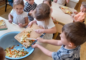 Dzieci z grupy drugiej wsypują warzywa do sałatki