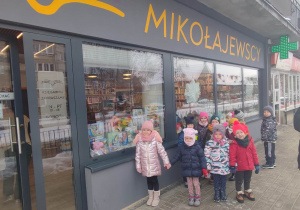 Dzieci z grupy czwartej stoją przed księgarnią