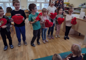 Dzieci stoją z pluszowymi sercami przy piosence o kochaniu