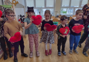 Piątka dzieci stoi z pluszowymi sercami do piosenki o kochaniu