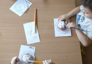 Dzieci malują pączki z masy solnej białą farbą