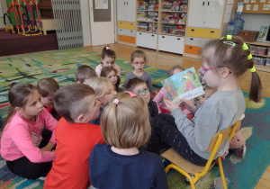 Dziewczynka czyta dzieciom książeczkę