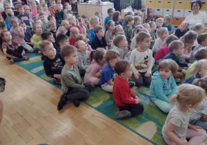 Przedszkolaki podczas koncertu siedzą na dywanie