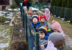 Dzieci stoją przy siatce ogródka działkowego