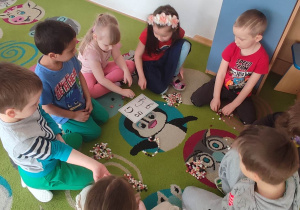 Dzieci układają literkę "g" z guzików