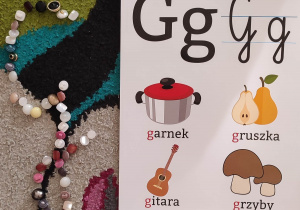 Wielka litera "g" ułożona z guzików przez dzieci