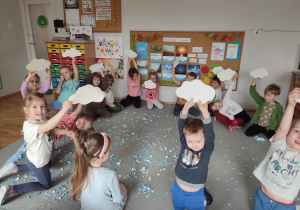 Przedszkolaki pokazują swoje deszczowe chmurki wycięte z papieru