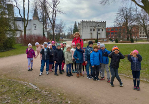 Dzieci z grupy piątej stoją w parku przy Zamku
