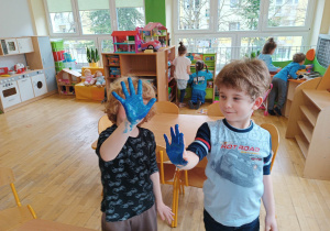 Dwóch chłopców z grupy trzeciej ma pomalowane dłonie na niebiesko