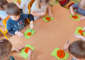 Dzieci rozmawują farbę na katrce pędzelkiem