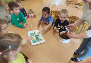 Przedszkolaki z grupy trzeciej podczas jedzenia banan w czekoladzie