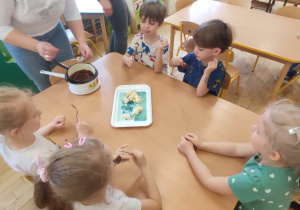 Dzieci z grupy czwartej podczas jedzenia banana w czekoladzie