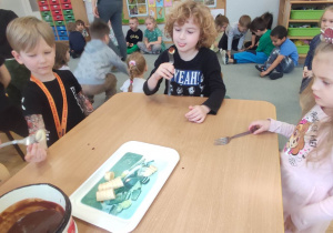 Dzieci z grupy trzeciej podczas jedzenia banana z czekoladą